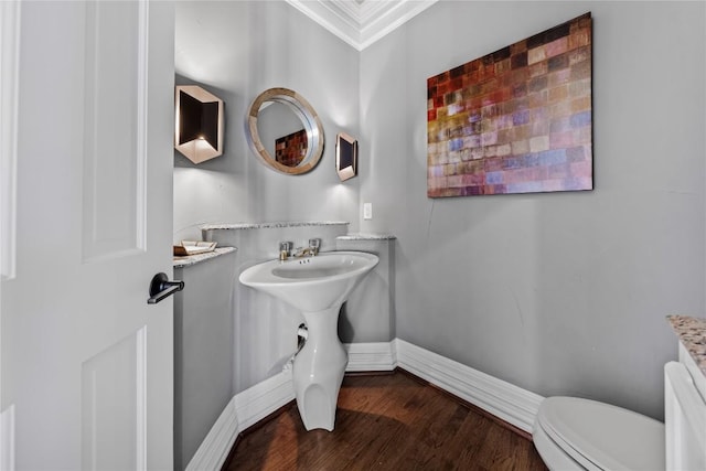 bathroom featuring baseboards, toilet, wood finished floors, and ornamental molding