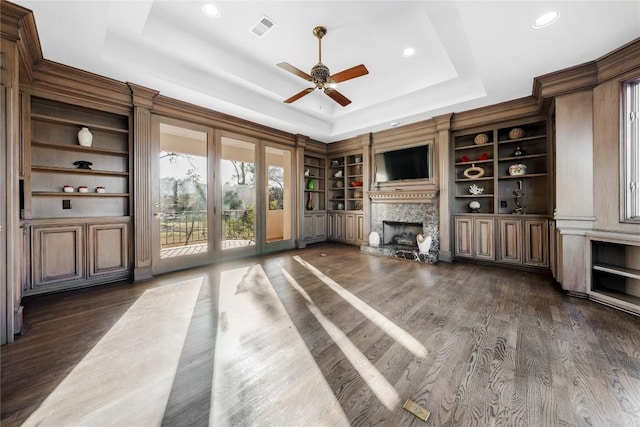 unfurnished living room with a tray ceiling, visible vents, dark wood-type flooring, and a fireplace