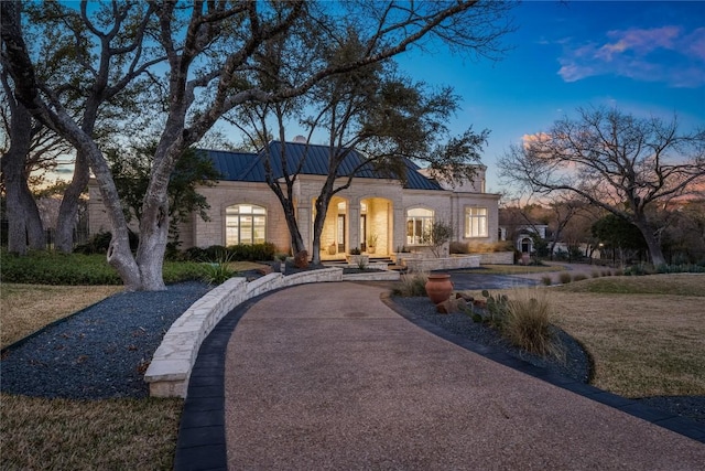 view of front of property featuring metal roof, driveway, and a standing seam roof