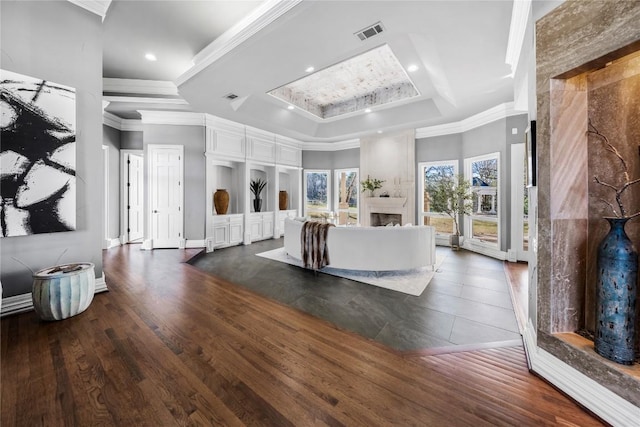 living room with a fireplace, a raised ceiling, crown molding, and dark wood-style flooring