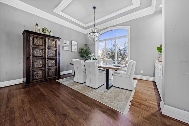 dining area with a raised ceiling, ornamental molding, wood finished floors, and a chandelier