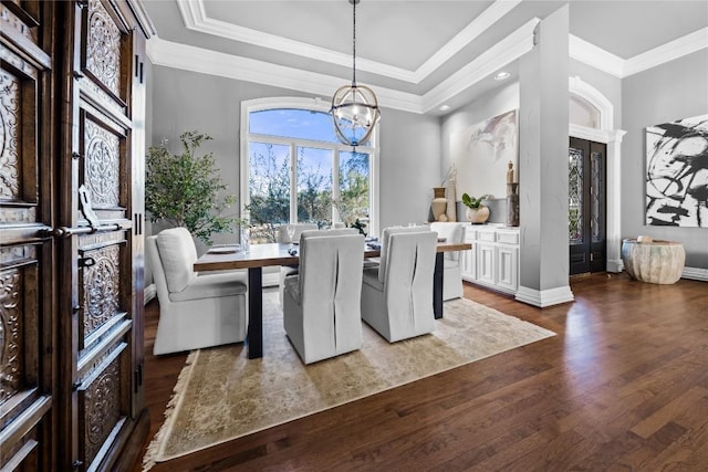 dining area featuring wood finished floors, baseboards, an inviting chandelier, a tray ceiling, and ornamental molding