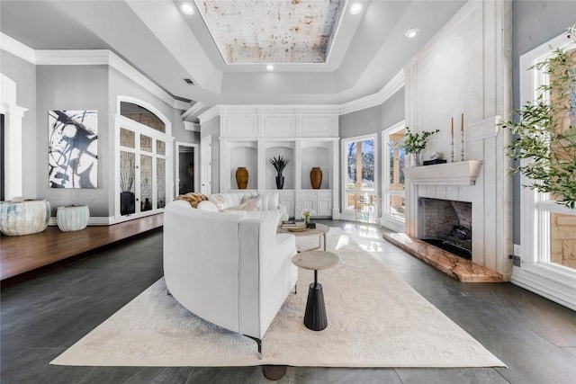 living area with ornamental molding, a premium fireplace, recessed lighting, a high ceiling, and a raised ceiling