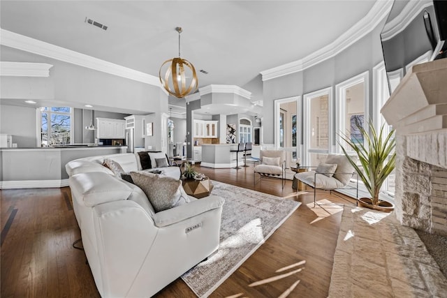 living area with baseboards, visible vents, dark wood finished floors, ornamental molding, and a chandelier