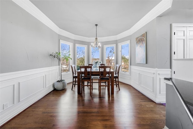 dining area with dark wood-type flooring, an inviting chandelier, ornamental molding, and wainscoting