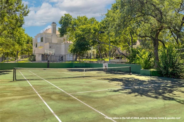 view of tennis court with community basketball court and fence