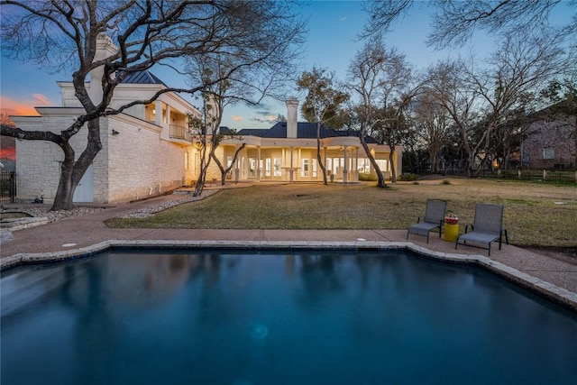 outdoor pool featuring a patio area and a lawn