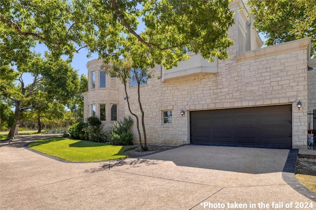 view of front of home with a garage, stone siding, and driveway