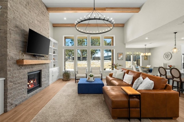 living room featuring a large fireplace, wood finished floors, beam ceiling, a towering ceiling, and an inviting chandelier