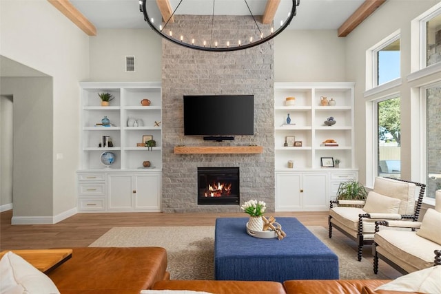 living room with visible vents, a fireplace, an inviting chandelier, light wood-style floors, and a towering ceiling