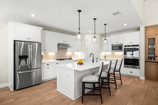 kitchen featuring light countertops, light wood-style floors, under cabinet range hood, and stainless steel appliances