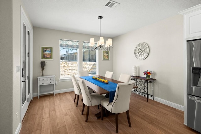 dining area featuring an inviting chandelier, baseboards, visible vents, and light wood-type flooring