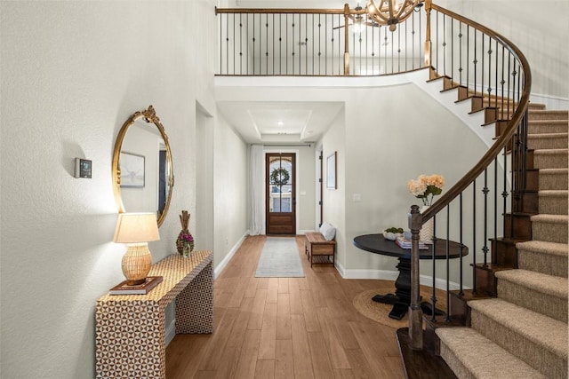 entryway with a towering ceiling, stairs, baseboards, and wood finished floors