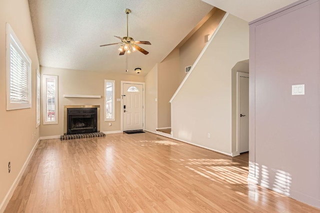 unfurnished living room with a wealth of natural light, visible vents, light wood-type flooring, and ceiling fan