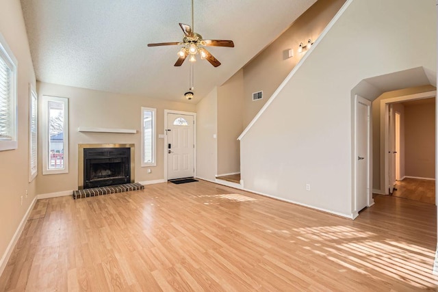 unfurnished living room featuring light wood finished floors, visible vents, a fireplace, and a ceiling fan