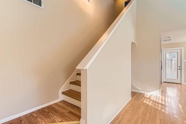 staircase with visible vents, baseboards, and wood finished floors