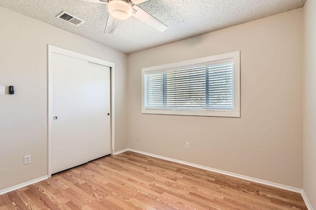 unfurnished bedroom with visible vents, a textured ceiling, light wood-type flooring, and baseboards