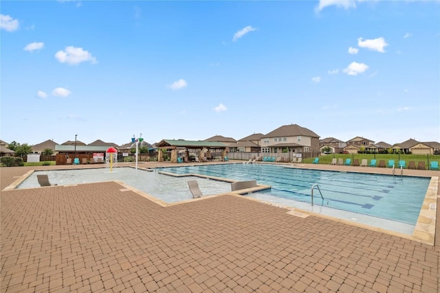 pool with a patio area, fence, and a residential view