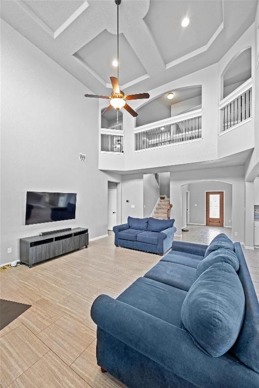 living room with stairway, coffered ceiling, baseboards, and a towering ceiling