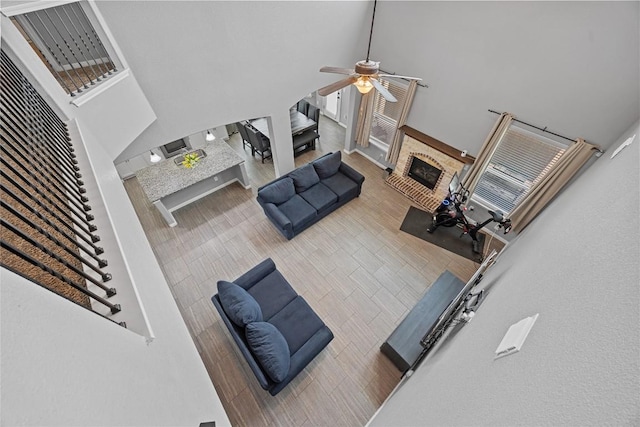 living room featuring a ceiling fan, a fireplace, and a towering ceiling