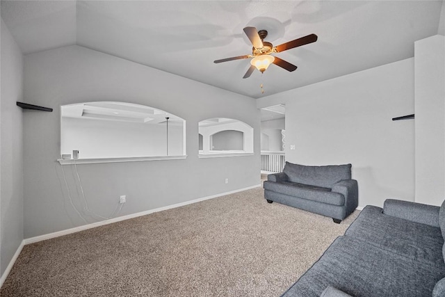 sitting room with lofted ceiling, a ceiling fan, arched walkways, carpet flooring, and baseboards