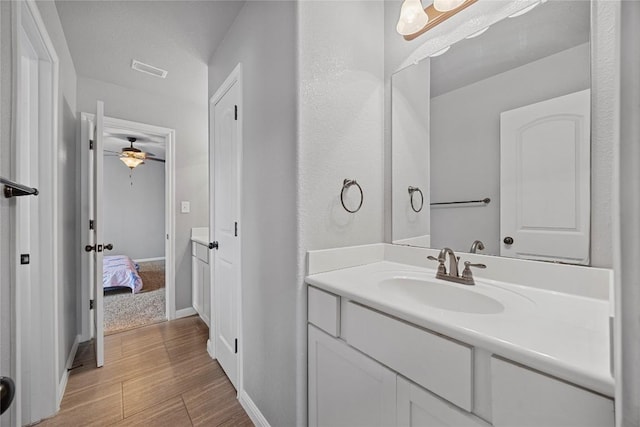 bathroom with vanity, visible vents, wood finished floors, and baseboards