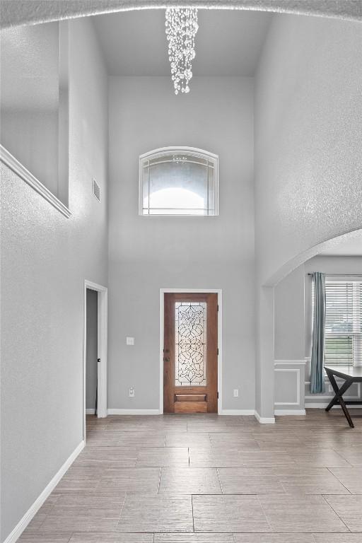 foyer with a chandelier, baseboards, a high ceiling, and wood finish floors