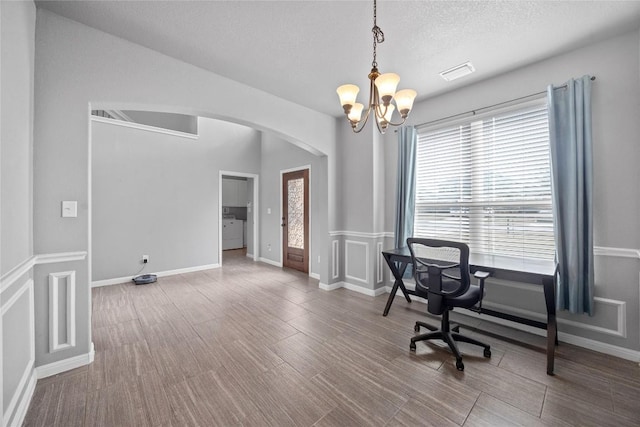 office with visible vents, wood finished floors, arched walkways, a notable chandelier, and a textured ceiling