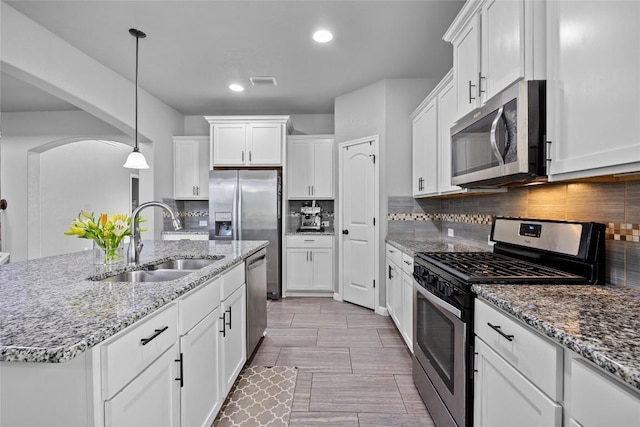 kitchen featuring visible vents, decorative backsplash, white cabinets, stainless steel appliances, and a sink