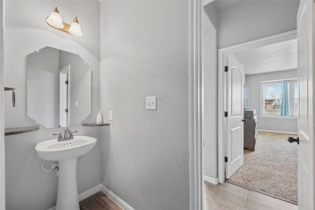 bathroom featuring a textured wall and baseboards