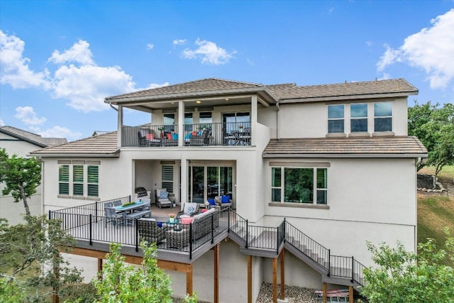 back of property with an outdoor living space, a tile roof, stairs, stucco siding, and a balcony