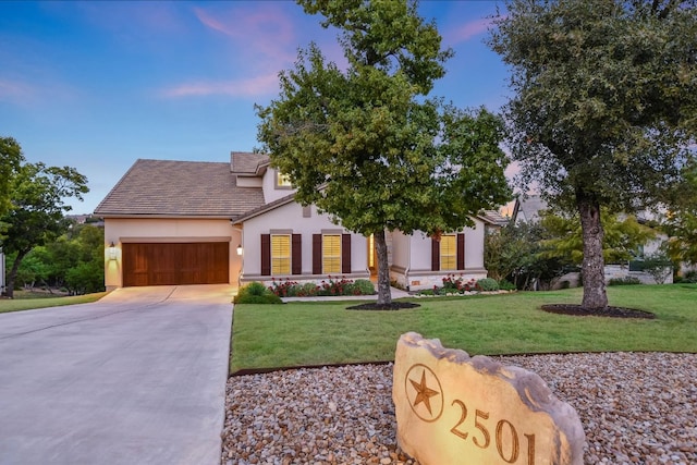 view of front of home featuring stucco siding, driveway, a front yard, and an attached garage