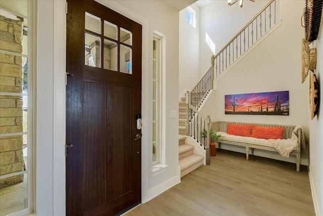 entrance foyer featuring visible vents, stairway, wood finished floors, and a high ceiling