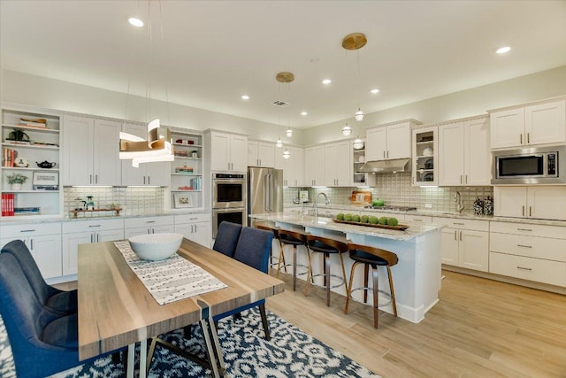 kitchen with open shelves, stainless steel appliances, under cabinet range hood, and white cabinetry