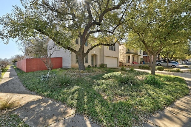 view of front of property with stucco siding, a garage, and fence