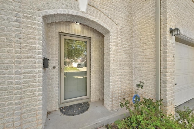 entrance to property featuring brick siding and an attached garage