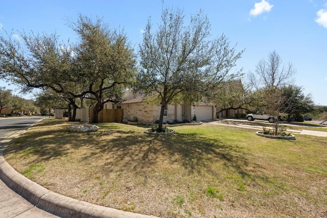 view of side of property featuring a garage, a yard, driveway, and fence