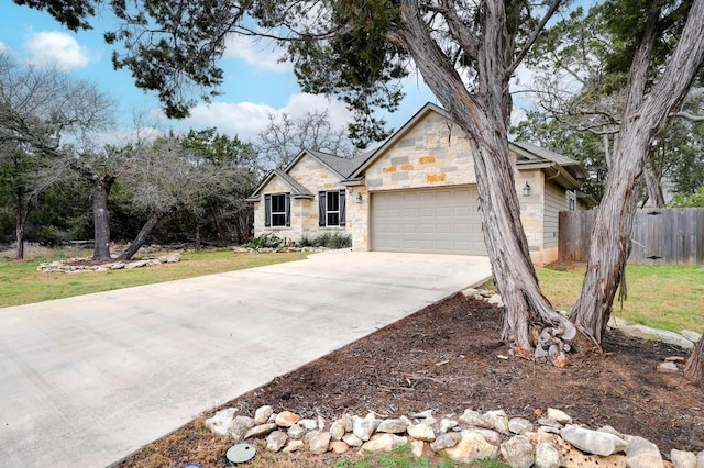 view of front of house featuring fence, an attached garage, concrete driveway, a front lawn, and stone siding