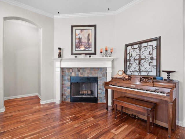 living area featuring a tiled fireplace, baseboards, and wood finished floors