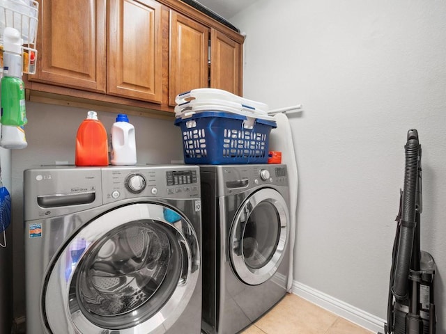 laundry room featuring cabinet space, light tile patterned flooring, washing machine and dryer, and baseboards