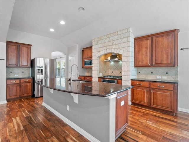 802 Wood Mesa Dr, Round Rock, TX 78665 - kitchen featuring stainless steel appliances, lofted ceiling, arched walkways, dark wood-type flooring, and tasteful backsplash