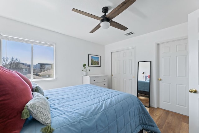 bedroom featuring a ceiling fan, wood finished floors, visible vents, and a closet