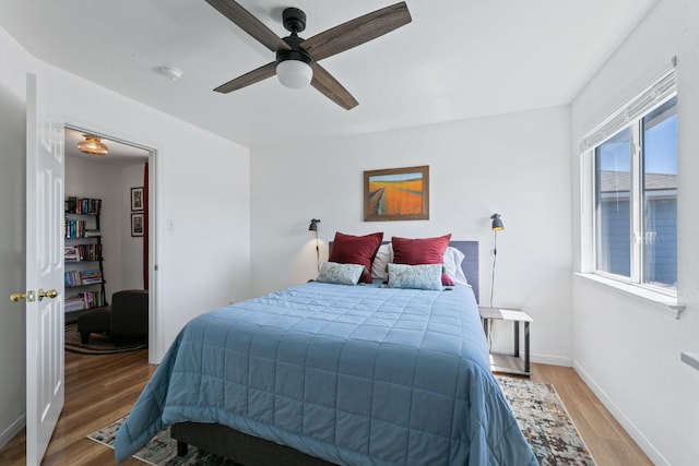 bedroom with light wood-style flooring, baseboards, and ceiling fan