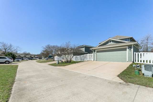 exterior space with a garage, roof with shingles, concrete driveway, and fence