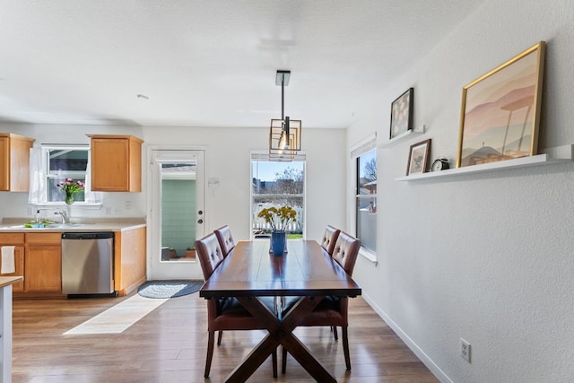 dining room with baseboards, light wood-type flooring, and a wealth of natural light