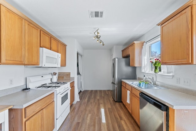 kitchen with wood finished floors, visible vents, a sink, stainless steel appliances, and light countertops