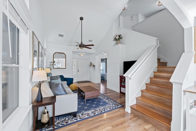 living area featuring visible vents, high vaulted ceiling, stairs, and wood finished floors