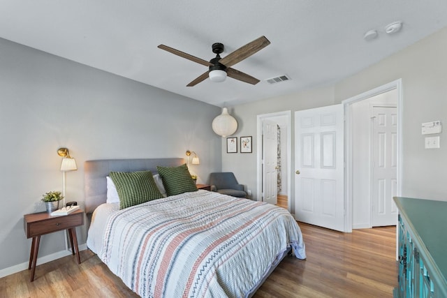 bedroom with ceiling fan, visible vents, baseboards, and wood finished floors