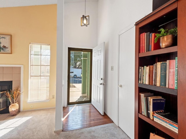 carpeted entryway featuring plenty of natural light, a fireplace, and a towering ceiling