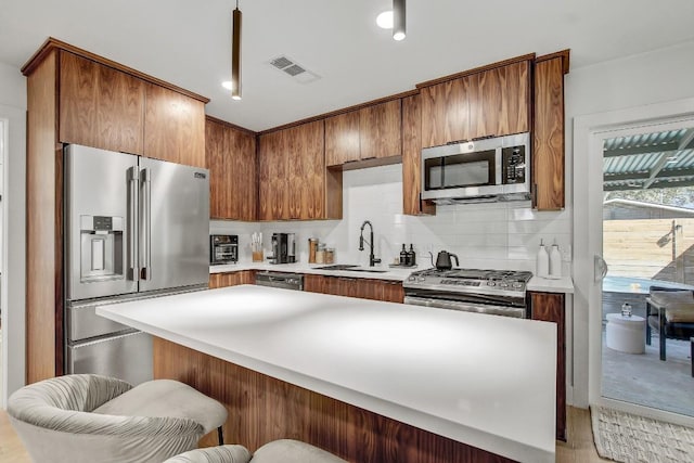 kitchen featuring tasteful backsplash, visible vents, light countertops, stainless steel appliances, and a sink